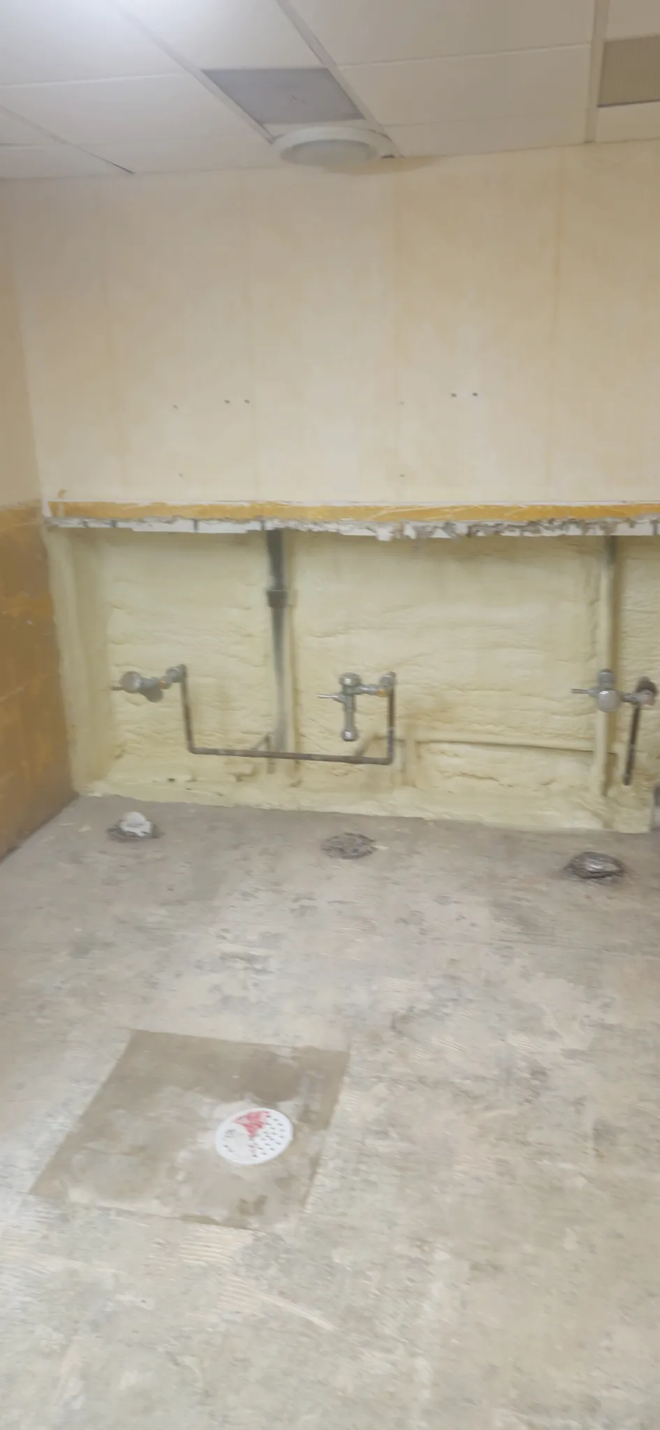 Closed-cell spray foam insulation behind plumbing in commercial space