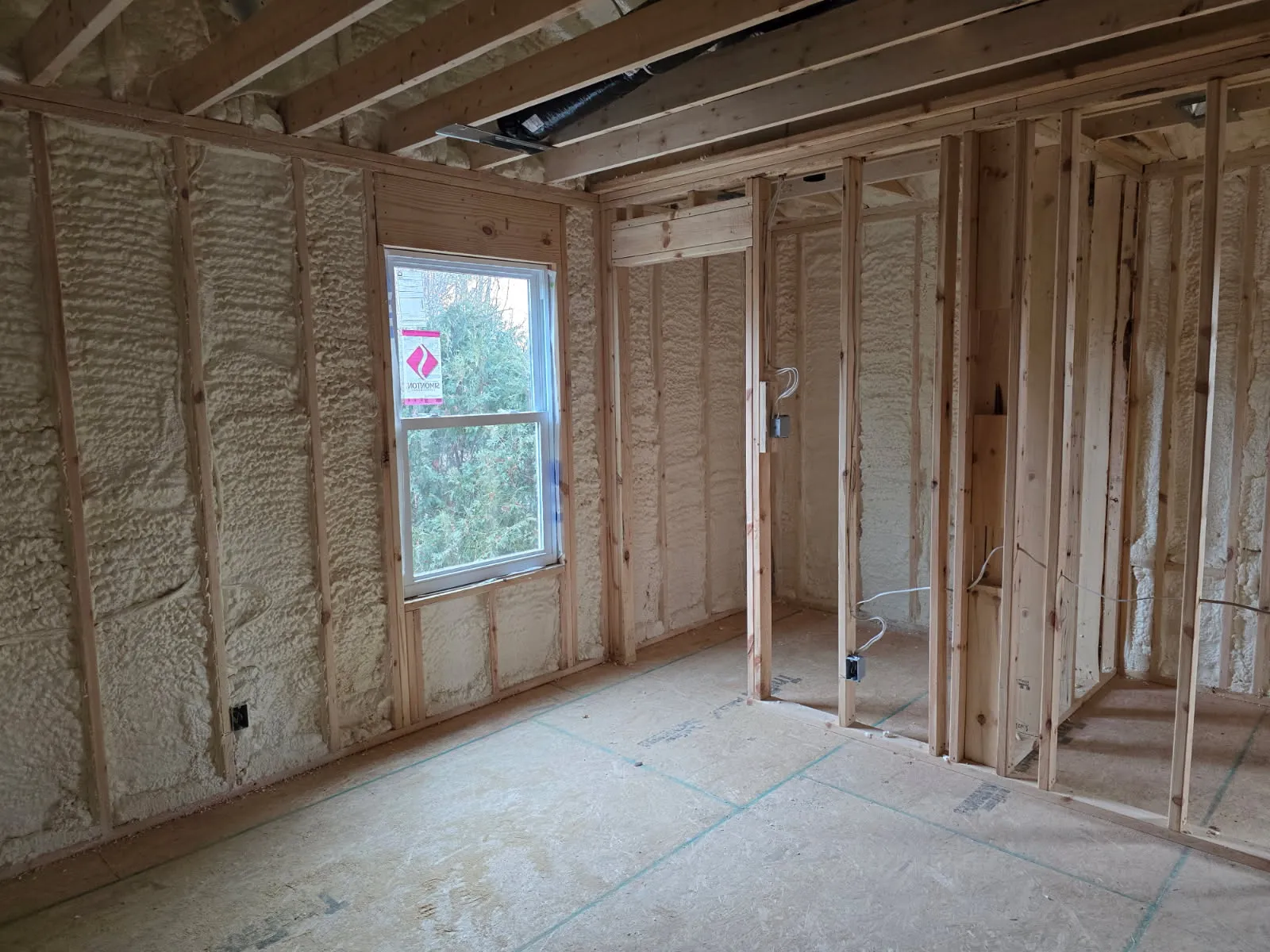 Room with vaulted ceiling, window, door framing, and electrical rough-in