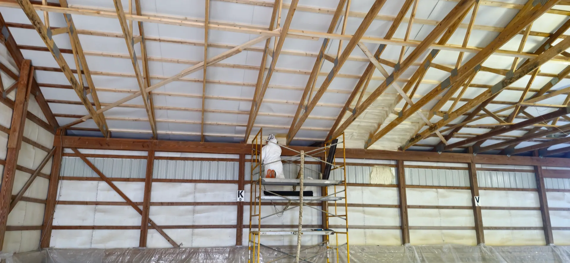 Worker spraying spray foam on pole barn roof