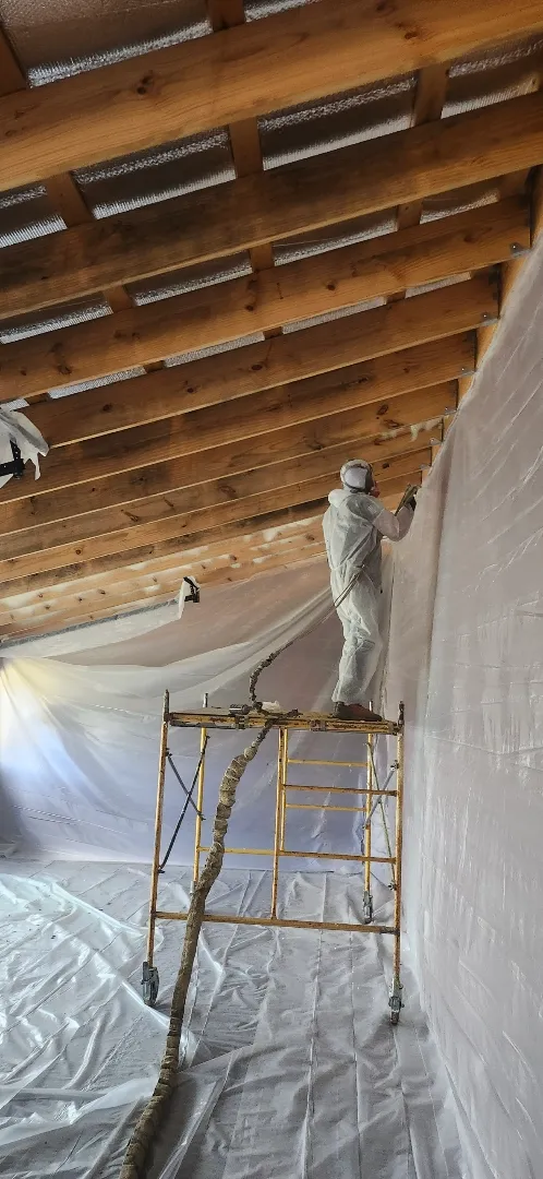 Worker spraying spray foam on residential ceiling
